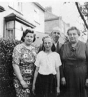 Family standing in front of house near bushes for a photo.