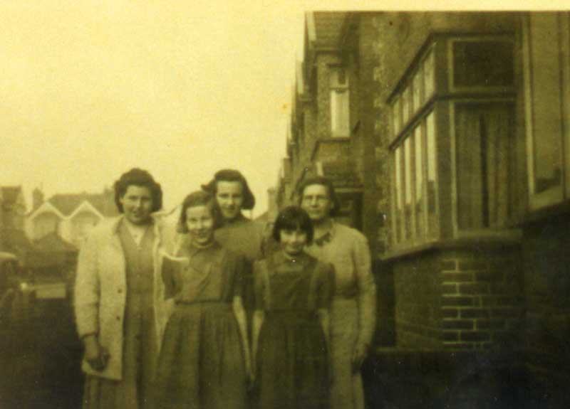 Five ladies young and middle aged, standing in front of the house for a photo.