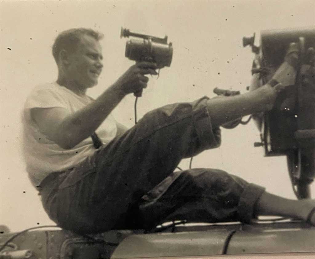 A young man sits on a ledge with his foot raised.