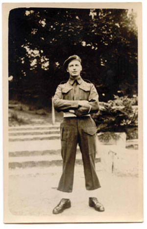 Young Hugh standing with arms folded, wearing military dress.