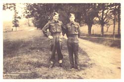 Young Leland and brother in military uniforms, standing near dirt road.
