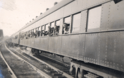 Several young men with heads out the windows of a passing train.