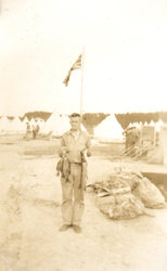 Young man holding fish with flag and tents in background.