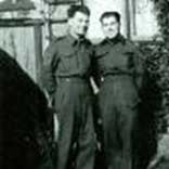 Old photo of two young soldiers in uniform, standing side by side.