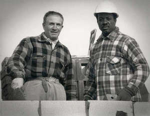 Two men wearing work clothing and hard hats.