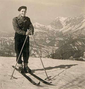 Young Leonardo with skis and poles in the Alps, posing for the camera.