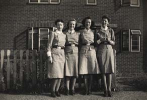 Four young women in army nursing uniform standing in front of a building.