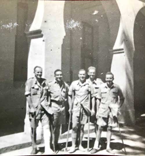 Black and white photo of five men holding crutches.