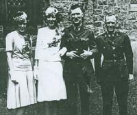 Newlyweds in front of the church with a man and a woman on each side. 