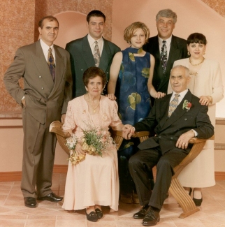 Coloured photo of older Pagano couple, seated with family standing behind.