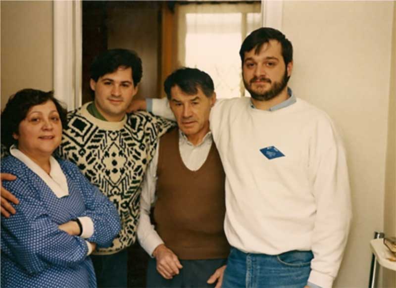 A family pose inside their home; mother, youngest son, father, oldest son.