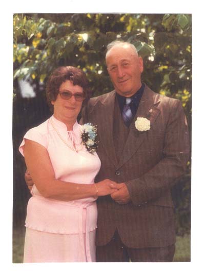Color photography of Barbara and George older, well dressed and flowers in the buttonhole.