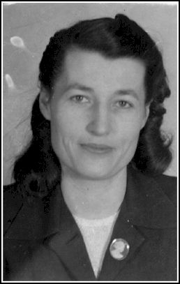 Head shot of smiling Marjorie, wearing a cameo on jacket lapel.