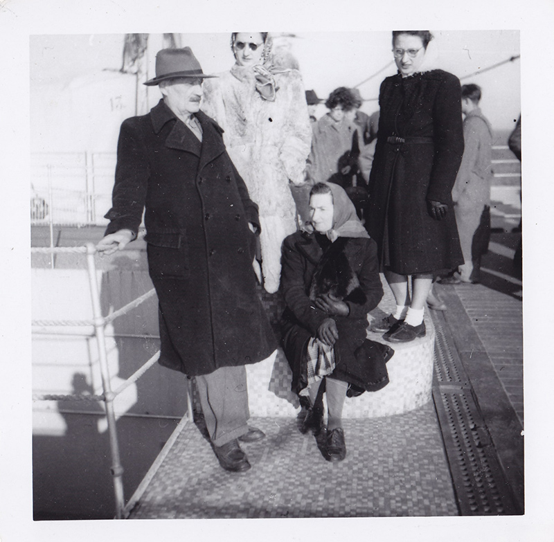 People dressed in warm clothing standing on the deck of a ship.