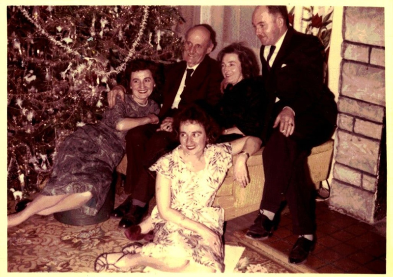 People seated in front of and around a Christmas tree.