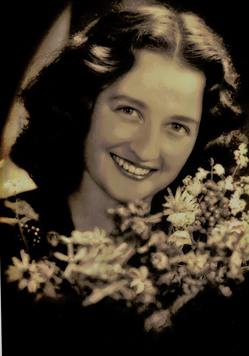 Young woman smiling for the camera as she holds a bouquet of flowers.