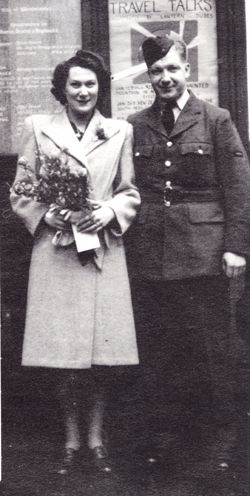 Man in military uniform with arm around woman holding bouquet.