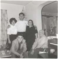 Two family members seated with three standing close by.