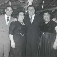 Two men and two women standing, dressed in nice clothing.