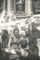The Orlando family seated on the stone wall surrounding Trevi Fountain.