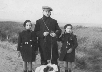 Man walking dog on a leash, with young daughter on either side.