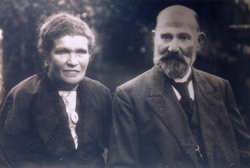 Woman and bearded man, both wearing dark-coloured clothing.