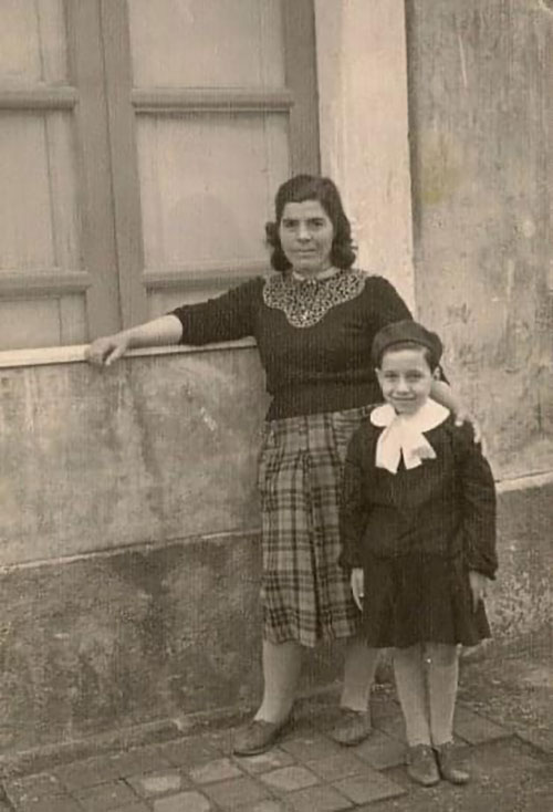 Archival image from 1950's Sicily; a young boy in school uniform and his mother.