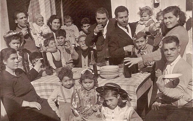 Large group of adults and children seated around a table.