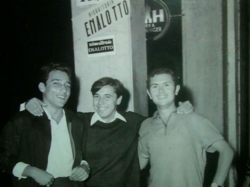 Archival image of three young men with arms around each other.