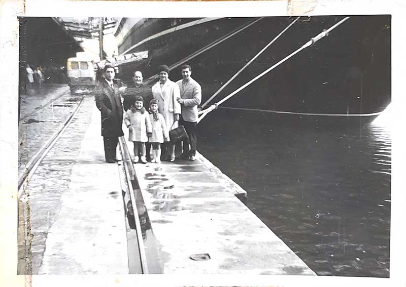 A family of six stand on the pier, waiting to board their ship.