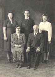 Family portrait with mother and father seated, three adult children standing behind.