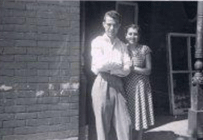 Man and woman standing on porch of house.