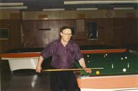 Color photograph of older Nikolas, preparing to play pool.