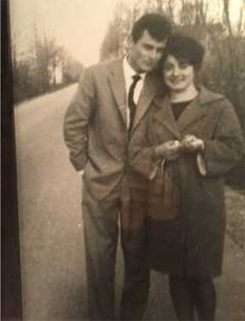 Black and white photo of young man and woman, standing on a dirt road