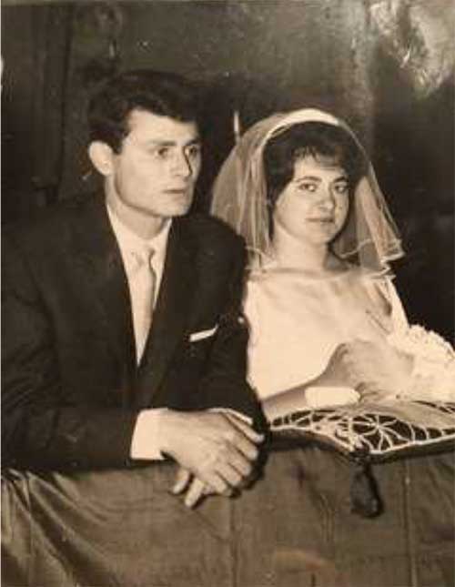 Black and white photo of young bride and groom kneeling in a pew