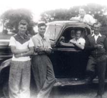 Five young men in and around an old model car.