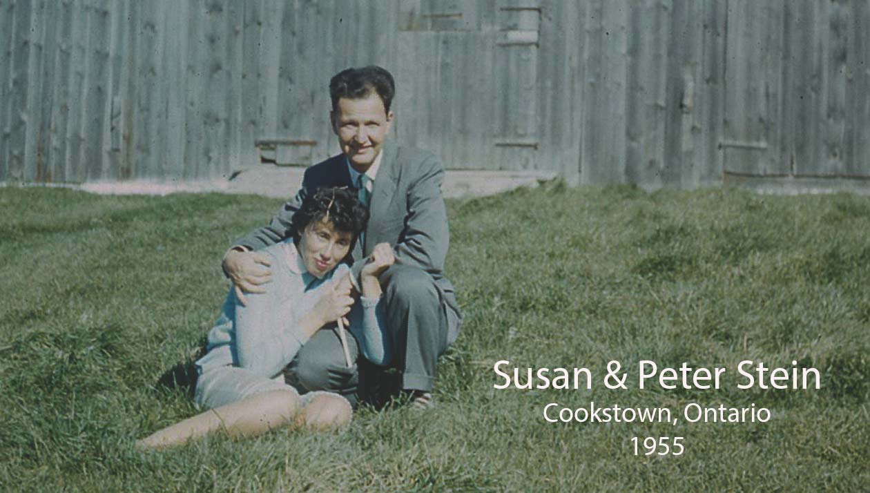 A Slovakian man and woman sitting in the grass at their farm, smiling at the camera.