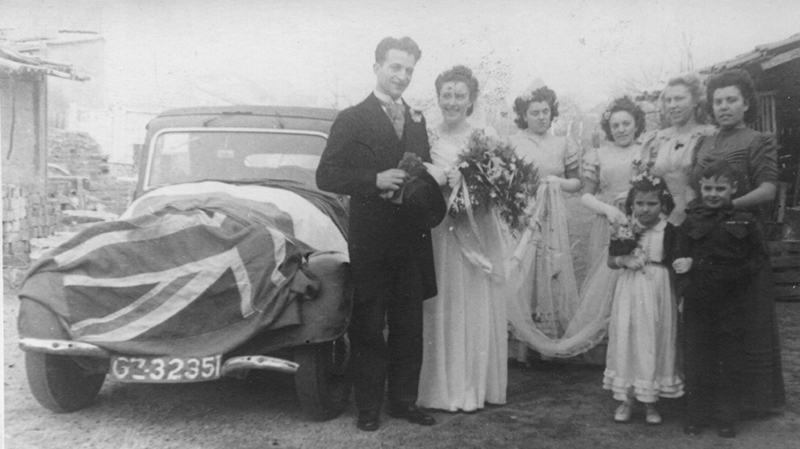Couple is standing next to a car with family.
