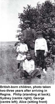 Man with three children standing in field in front of tree.