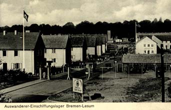 Yellowed postcard showing road with several rows of houses of Germany camp.