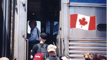 People boarding a train with Canadian flag pictured on side.