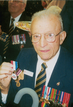 Coloured photo of Ernest as an older man, proudly showing his medals.