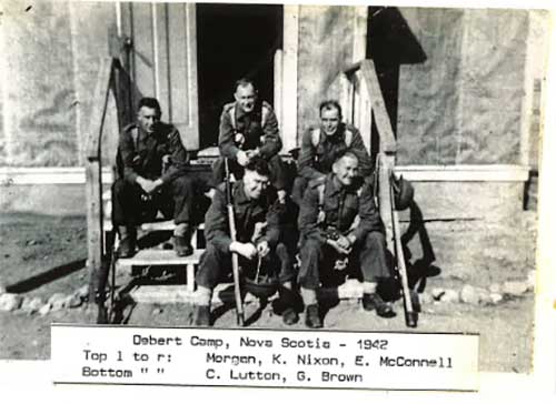Five military men sit on wooden steps and smile for the camera.