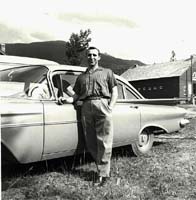 Young man standing near an old car.