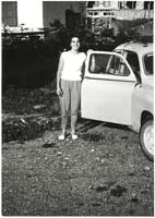 Young woman standing by the open door of a car.