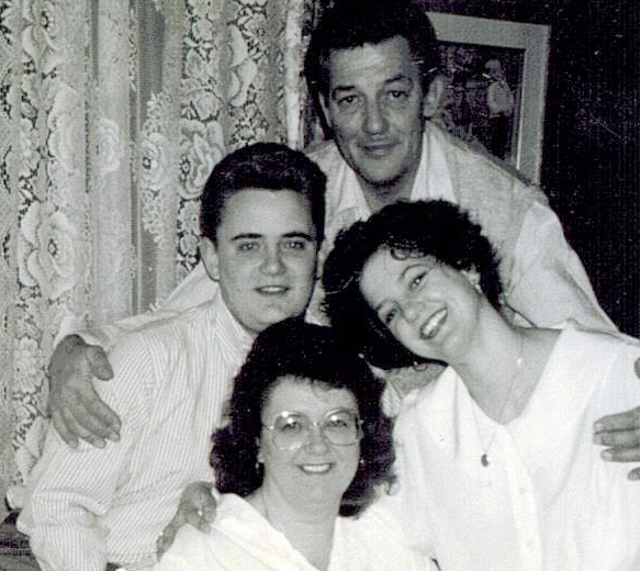 Old black and white photo of a family of four, smiling for the camera.