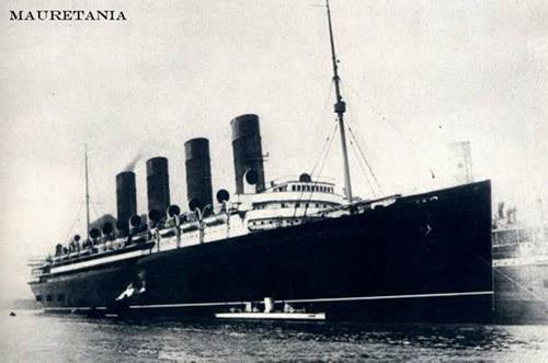 Black and white photo of ship from front side with Mauretania written on top left corner.