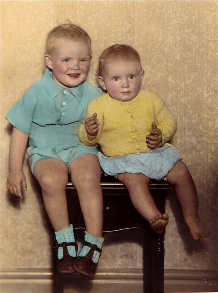 Two young boys, seated on stool.