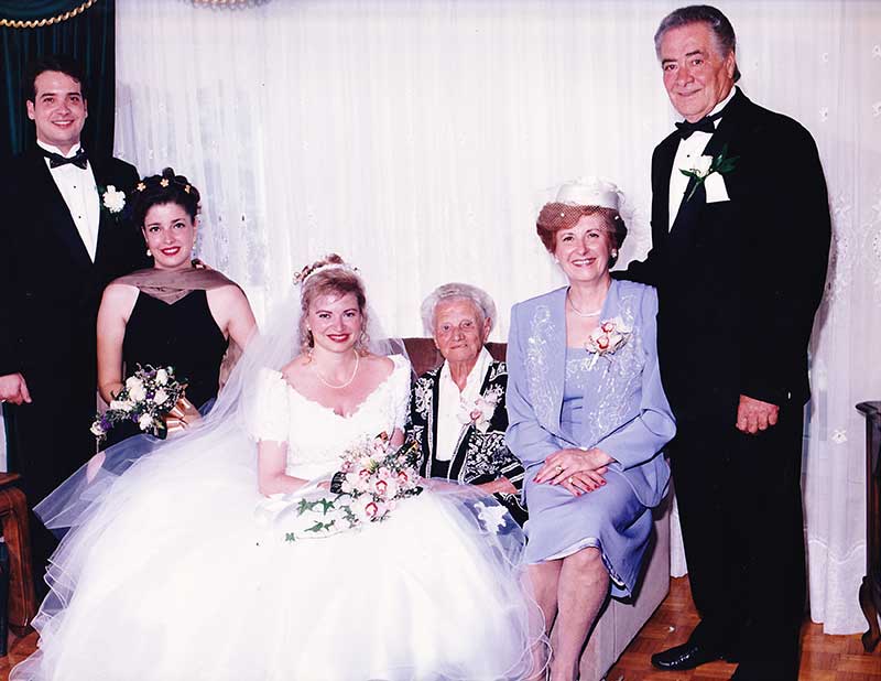 Bride sits on a couch surrounded by five family members.