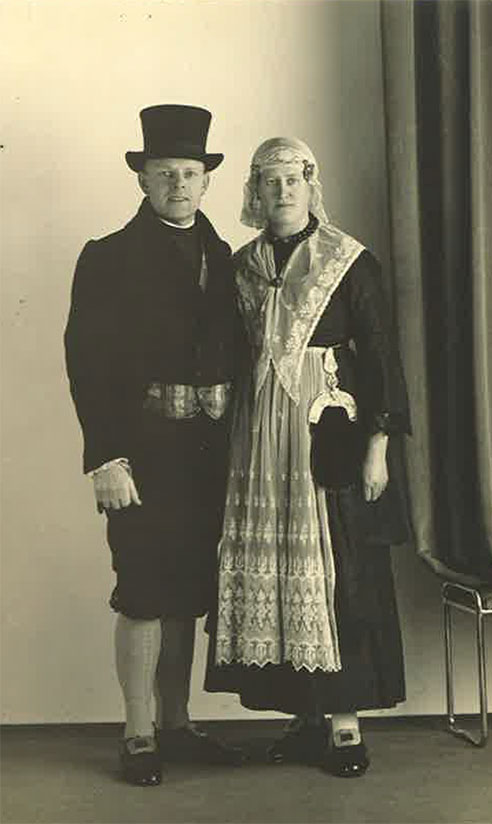 Young man and woman standing in front of a wall wearing costumes.